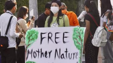 Joven mujer con un gran cartel en el que se lee «¡Liberad a los activistas de Mother Nature!».