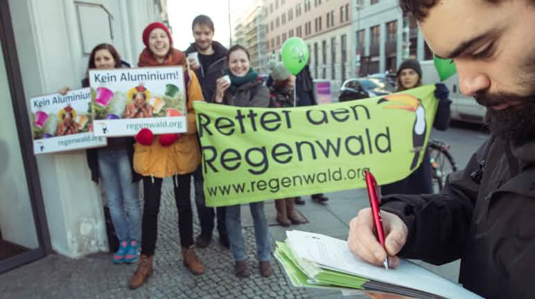 Defender a quienes defienden, acabar con las demandas intimidatorias Activistas de Salva la Selva/Rettet den Regenwald con pancartas