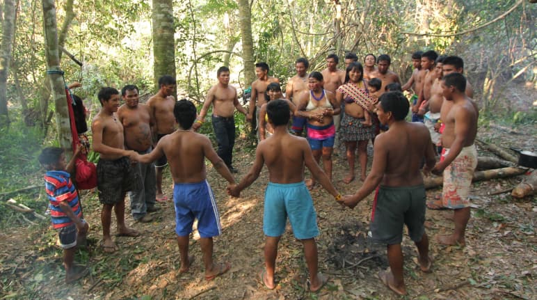 Indígenas Ka’apor -niños, mujeres y hombres- se dan la mano y forman un círculo. Se encuentran en su territorio, en la Amazonía brasileña