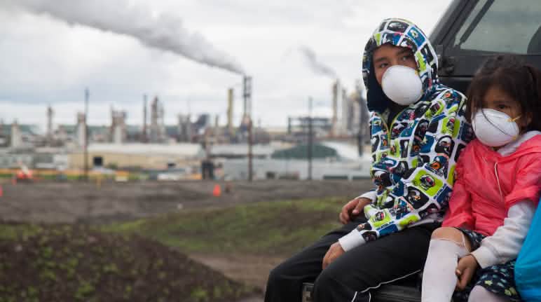 Muchas personas alrededor del mundo sufren violaciones de derechos por la actividad corporativa Niños con máscaras protectoras durante la caminata "Healing Walk" en 2013 contra una mina de arenas bituminosas