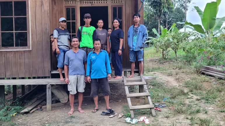 Visita de Salva la Selva Nueve personas, incluido un representante de Salva la Selva, delante de una casa de madera