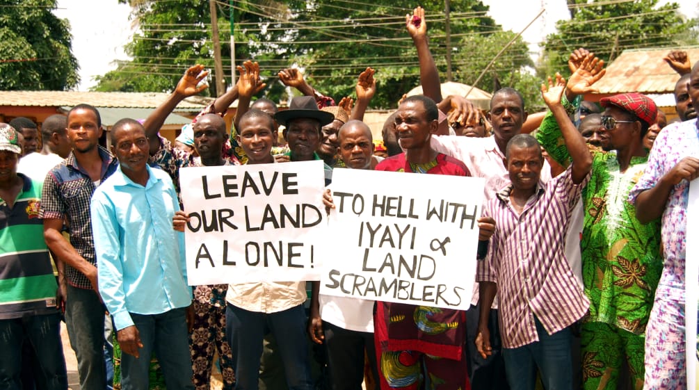 En protesta contra Okomu Oil Palm Oil en Nigeria, algunos afectados sostienen pancartas con leyendas como "Dejen nuestras tierras en paz" y otras