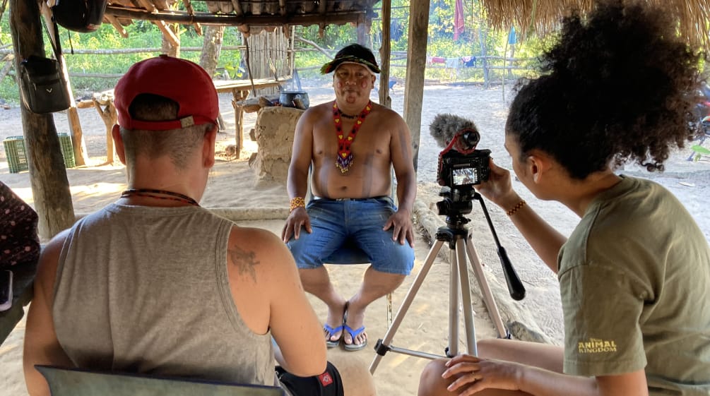 Dos periodistas de The Intercept de espaldas durante la entrevista en vídeo con el líder indígena Itahu Ka'apor, quien se encuentra de frente.