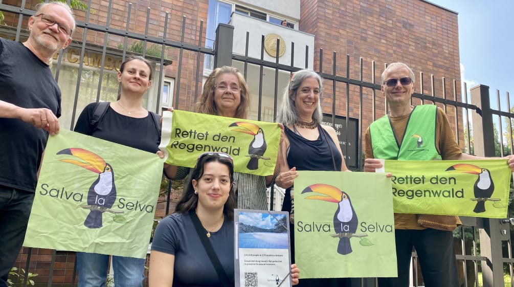 6 personas ante el edificio de la embajada, sosteniendo la petición y las pancartas de Salva la Selva/Rettet den Regenwald