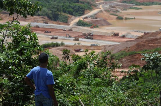 Campesino mira mina a cielo abierto desde el bosque