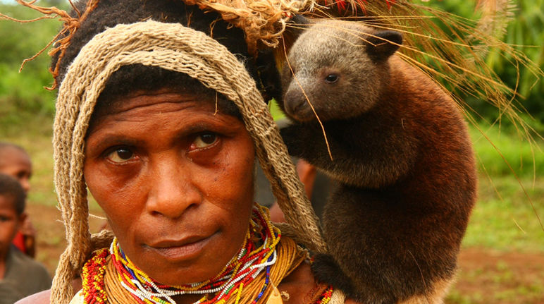 Mujer de Papua con un canguro bebe al hombro